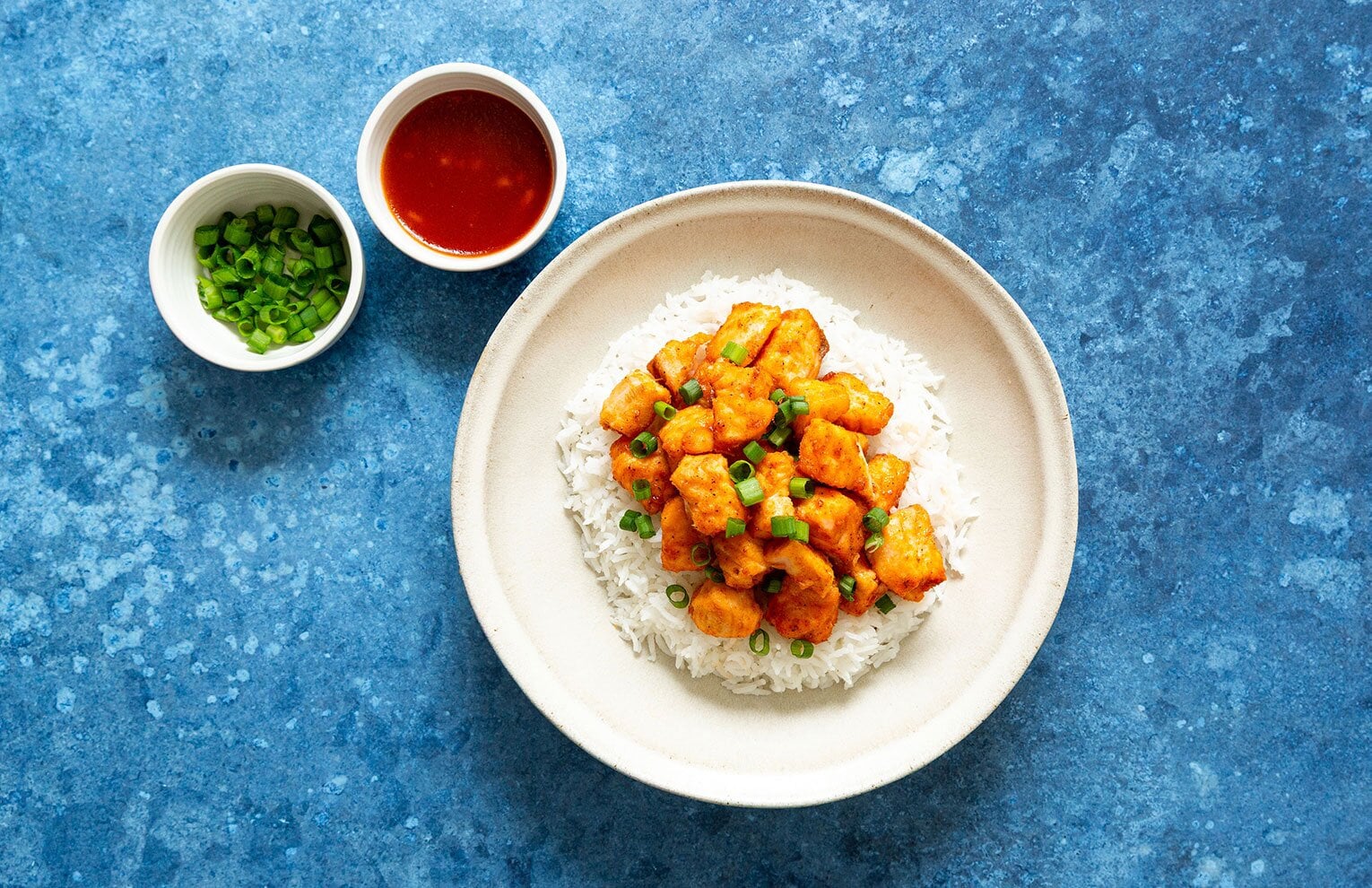 Fried salmon bites coated in an apple bourbon sauce atop rice.